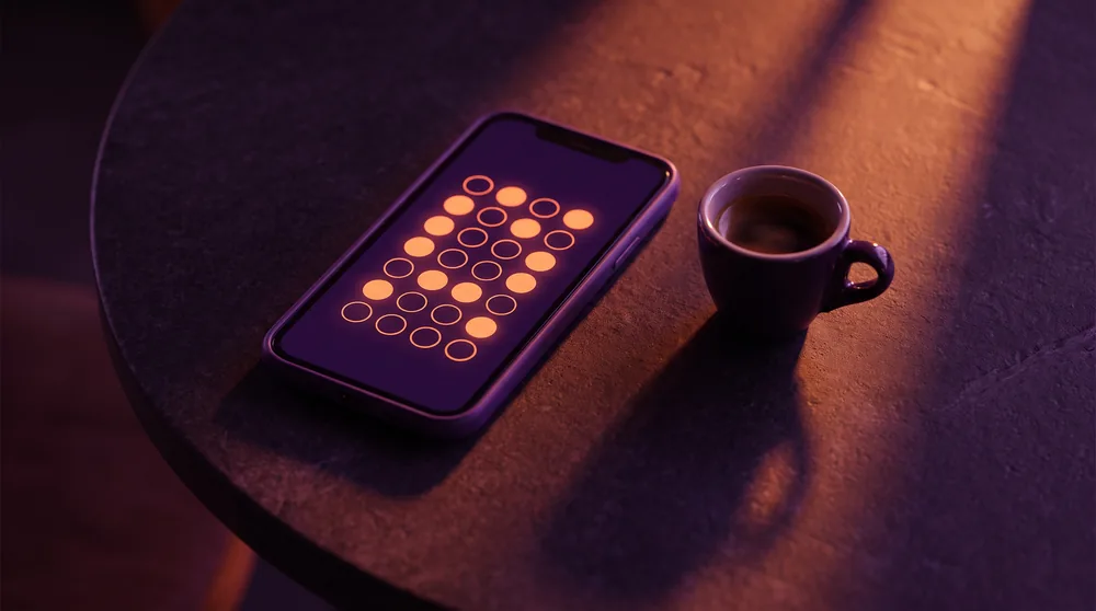 A phone on a cafe table showing a digital loyalty stamp card beside an espresso