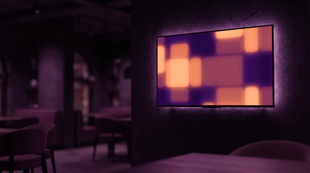A wall-mounted screen in a darkened restaurant displaying a digital menu board